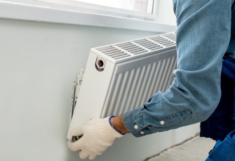 an image of a man removing a radiator from off the wall